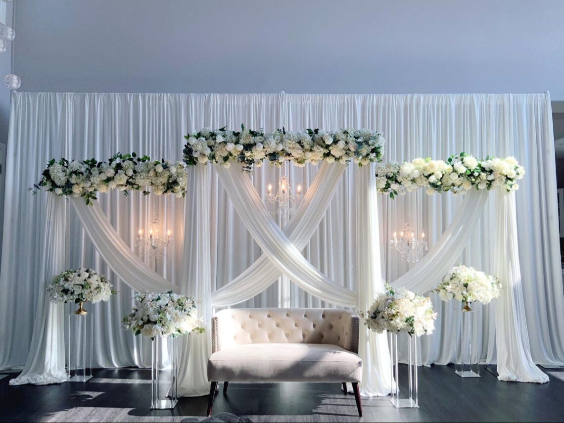 ELEGANT FLORAL OASIS: White Draped Backdrop with Crystal Chandeliers